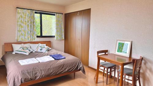 a bedroom with a bed and a table with a chair at Torinami Fuji View House in Fujinomiya