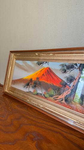 a painting of a mountain in a frame on a table at Torinami Fuji View House in Fujinomiya