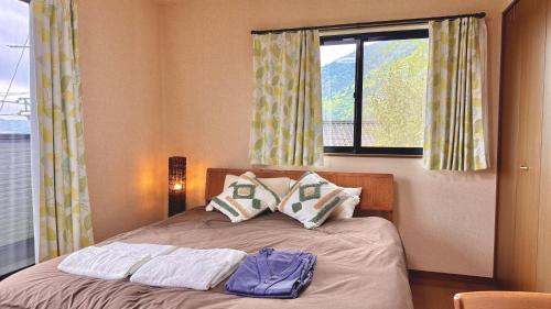 a bedroom with a bed with two pillows and a window at Torinami Fuji View House in Fujinomiya