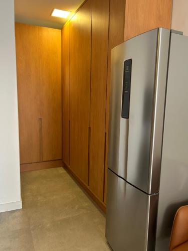 a kitchen with a stainless steel refrigerator and wooden cabinets at Estúdio ao lado da Praia - Rifaina in Rifaina