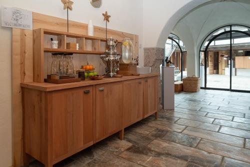 a kitchen with wooden cabinets and a tile floor at Hammerack Hotel, SPA & Wellness in Malborghetto Valbruna