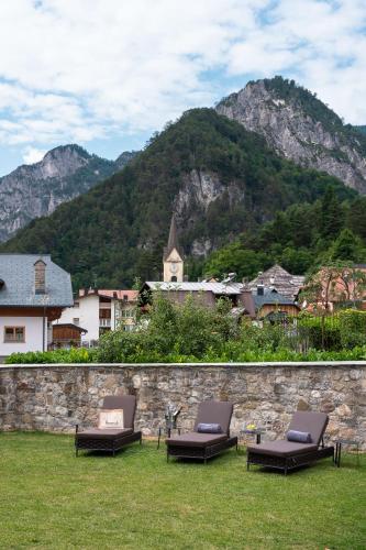 a group of chaise lounges on a lawn with a mountain at Hammerack Hotel, SPA & Wellness in Malborghetto Valbruna