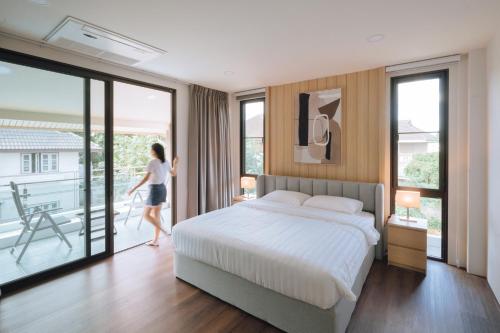 a woman walking in a bedroom with a bed and a balcony at Ma-Umi Chiang Mai pool villa 5 BRs - 10 mins to city center and Airport in Chiang Mai