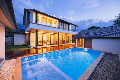 a house with a swimming pool in front of a house at Ma-Umi Chiang Mai pool villa 5 BRs - 10 mins to city center and Airport in Chiang Mai