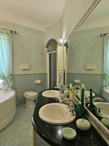 a bathroom with two sinks and a toilet and a mirror at Luna Domus in Ozieri