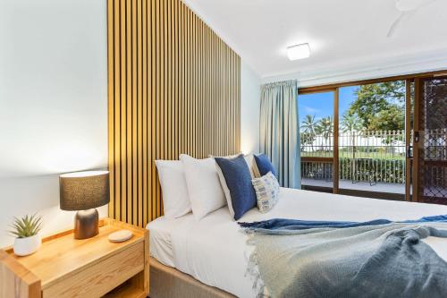 a bedroom with a bed and a large window at Rainforest & Reef Retreat - Esplanade Ground-Floor Apartment in Cairns North