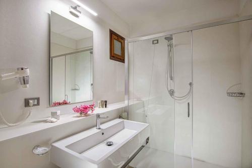 a white bathroom with a sink and a shower at Hotel Baia Imperiale in Campo nell'Elba