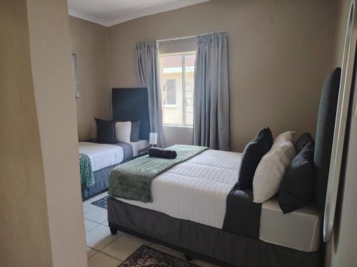 ein Schlafzimmer mit zwei Betten und einem Fenster in der Unterkunft Cornelia Place in Sunridge Park