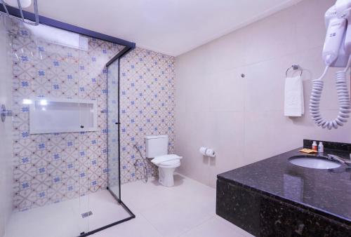a bathroom with a shower and a toilet and a sink at Hotel Village Enseada in Ubatuba