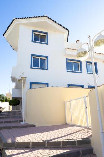a white house with blue windows and a fence at Casanova 20G Calpe in Calpe