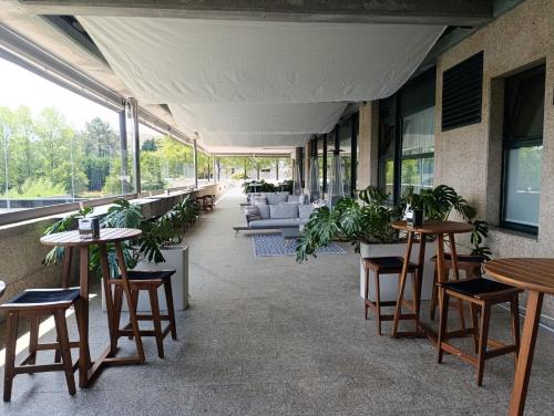 a restaurant with tables and chairs and plants at Oca Puerta del Camino Hotel in Santiago de Compostela