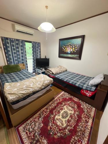 a bedroom with two beds and a rug at Shirahama in Miyazaki