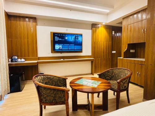 a room with a table and two chairs and a tv at The Grace Residency - Gomtinagar, Lucknow in Lucknow