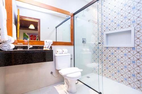 a bathroom with a toilet and a glass shower at Hotel Village Enseada in Ubatuba