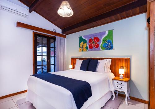 a bedroom with a large white bed and a window at Hotel Village Enseada in Ubatuba