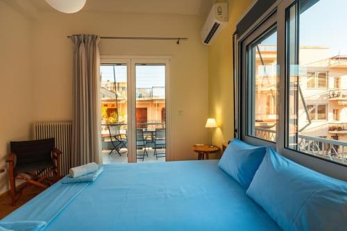 een slaapkamer met een blauw bed en een groot raam bij Upscale Modern Escape in the Historic Center in Kalamata