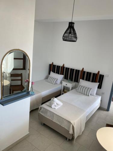 two beds in a room with a mirror at Emmy Rooms in Armenistis