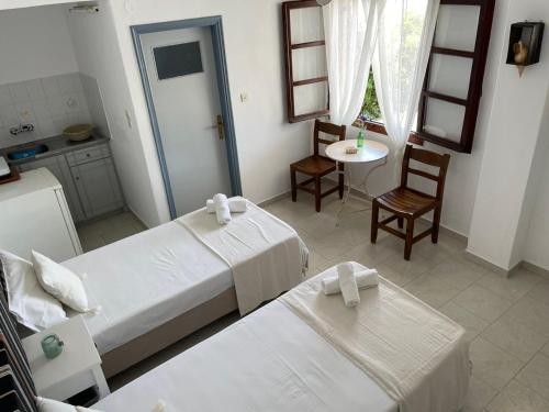 a hotel room with two beds and a table and a kitchen at Emmy Rooms in Armenistis