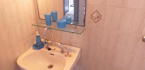 a bathroom with a sink with a mirror and some cups at Emmy Rooms in Armenistis