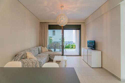 a living room with a couch and a tv at SithoniaRS Emerald Luxury Apartment in Nikiti