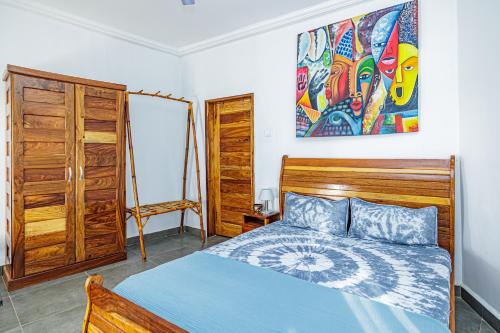 a bedroom with a bed and a painting on the wall at TinJaLa Lodge in Brufut