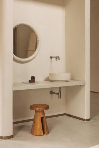 a bathroom with a sink and a mirror and a stool at Jonojé Luxury Suites in Bruges