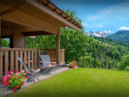 a porch of a house with a chair and flowers at Chalet Ours Rouge - OVO Network in Le Grand-Bornand