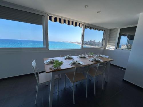 a dining room with a table and chairs with a view of the ocean at Tahití9H in El Campello