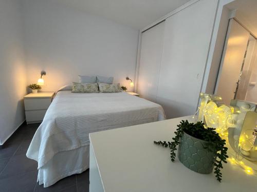 a white bedroom with a bed and two tables at Tahití9H in El Campello