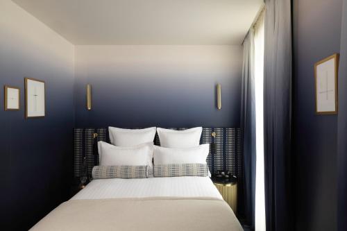 a bedroom with blue walls and a bed with white pillows at Hôtel Filigrane & Spa in Paris