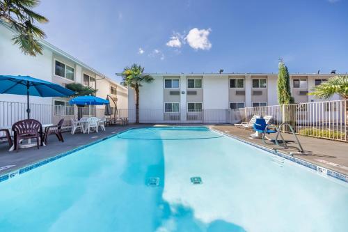 a swimming pool with chairs and umbrellas in front of a building at Studio 6 Seattle, WA Sea Tac Airport South in SeaTac