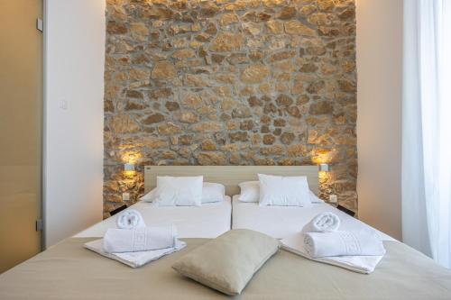 two beds in a bedroom with a stone wall at Villa Erika Crikvenica in Crikvenica