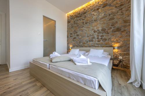 a large bed in a room with a stone wall at Villa Erika Crikvenica in Crikvenica