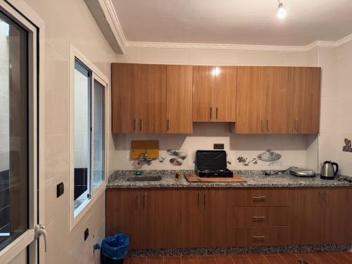 a kitchen with wooden cabinets and a counter top at Appartement très calme en face aéroport sania Ramel Tetouan in Tetouan