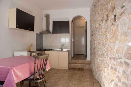 a kitchen with a table and a stone wall at Holiday home in Novi Vinodolski 15408 in Novi Vinodolski