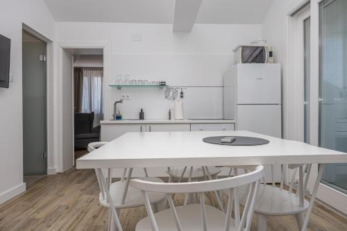 a white kitchen with a white table and chairs at Villa Erika Crikvenica in Crikvenica