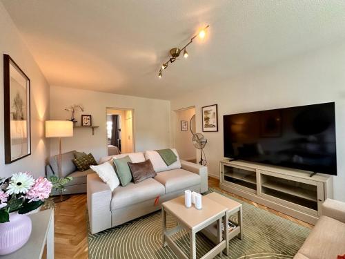 a living room with a couch and a large flat screen tv at Prinshöjden Hotel - Smart Digital Apartments & Villas in Katrineholm