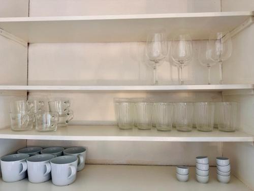 a shelf filled with glasses and wine glasses at Prinshöjden Hotel - Smart Digital Apartments & Villas in Katrineholm