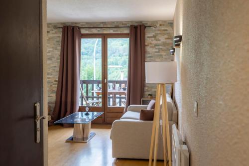 a living room with a couch and a table and a window at La Ruinée Appartement chaleureux à proximité des pistes et commodités in Briançon