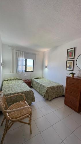 a hotel room with two beds and a chair at Golden Views Apartment in San Bartolomé