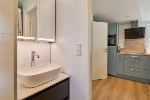 baño blanco con lavabo y cocina en Ostseecamp Ferienhaus "Sauerländer", en Scharbeutz