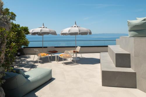 a patio with two umbrellas and a table and chairs at Kuk Oaza Luxury Villas in Makarska