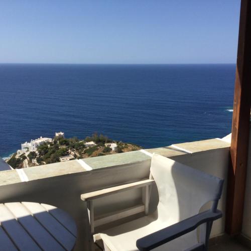 a white chair sitting on a balcony overlooking the ocean at Hermes-Ios Rooms To Let in Ios Chora