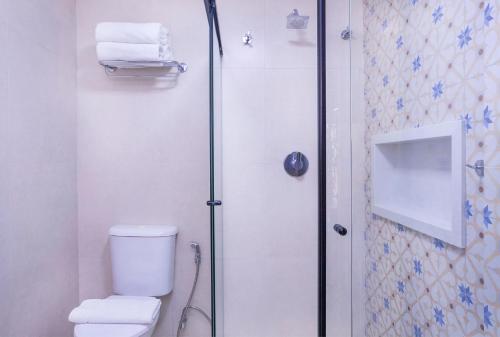 a bathroom with a shower and a toilet and towels at Hotel Village Enseada in Ubatuba
