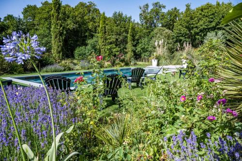 a garden with purple flowers and chairs and a pool at Mini gîte royal in Sainte-Gemme-la-Plaine