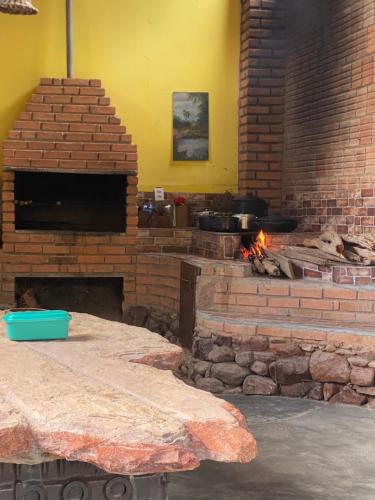 a brick oven with a table and a fireplace at Sítio Estrela da Manhã Hospedagem e Lazer in Palmeiras