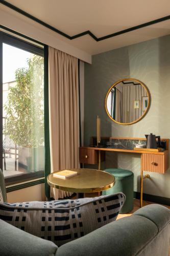 a living room with a couch and a table and a mirror at Hôtel Filigrane & Spa in Paris