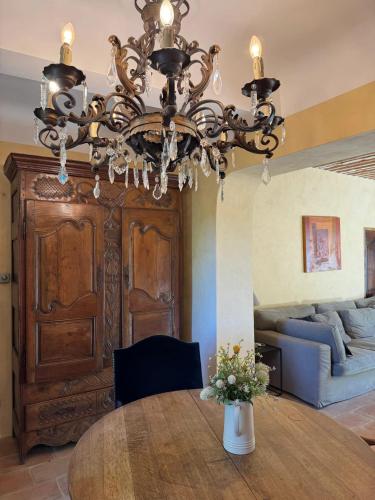 a chandelier in a living room with a table and a couch at Villa spacieuse avec jardin à Saignon in Saignon