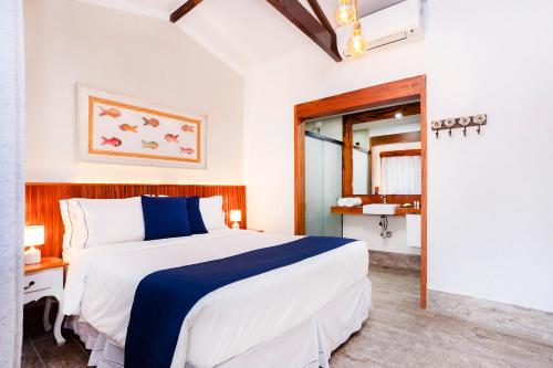 a bedroom with a large bed and a bathroom at Hotel Village Enseada in Ubatuba