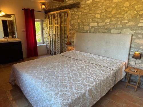 a bedroom with a bed and a stone wall at Villa spacieuse avec jardin à Saignon in Saignon